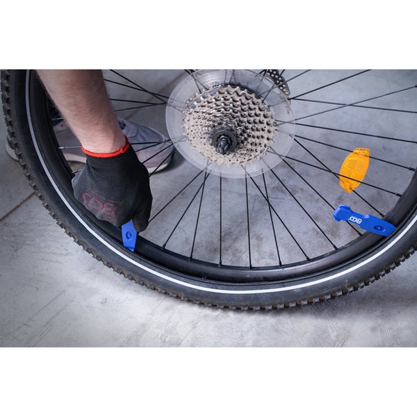 Anwendung von Reifenhebern zum Demontieren eines Fahrradreifens von der Felge.