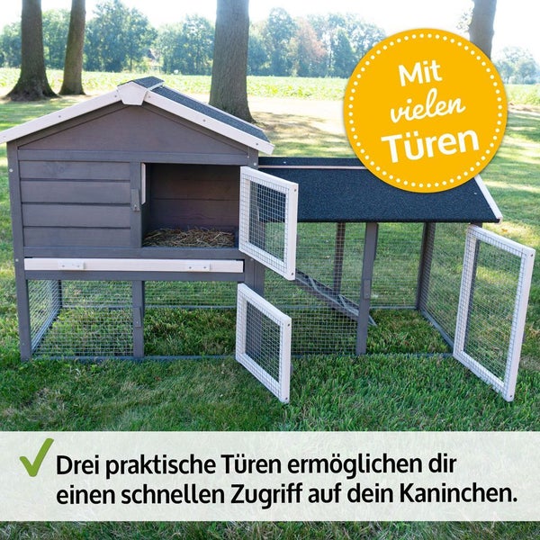 Zweistöckiger Kaninchenstall aus Holz mit integriertem Freilaufgehege und drei geöffneten Gittertüren für einfachen Zugang auf einer Rasenfläche.