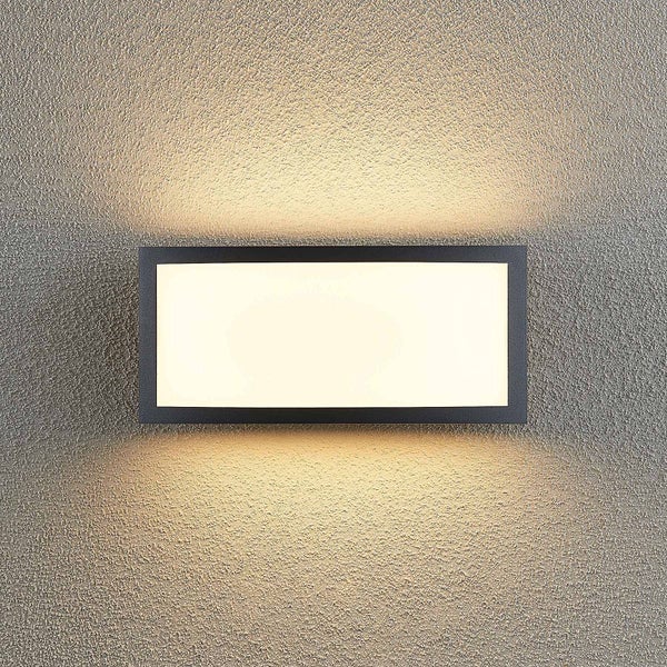 Rechteckige Außenwandleuchte mit schwarzem Metallrahmen und warmweißem Lichtaustritt an einer strukturierten Wand.