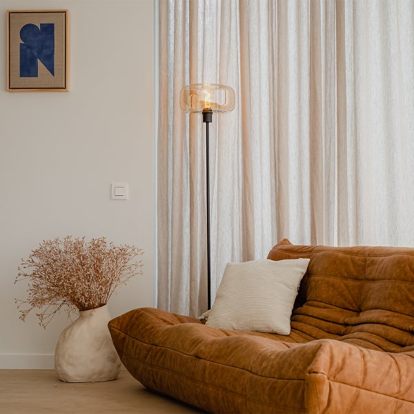 Wohnzimmer mit braunem Sofa, Stehlampe und Dekorationsgegenständen