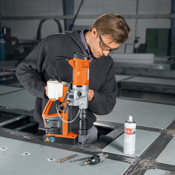 Ein Mann bedient eine Magnet-Kernbohrmaschine auf einer Metalloberfläche in einer Werkstatt.