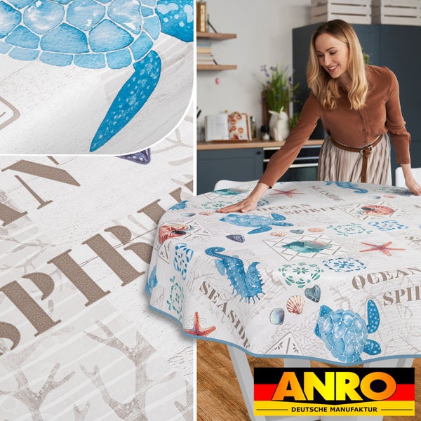 Runde Wachstuchdecke mit Meeresmotiven auf einem Tisch, im Hintergrund eine Frau und die ANRO Deutsche Manufaktur Logo
