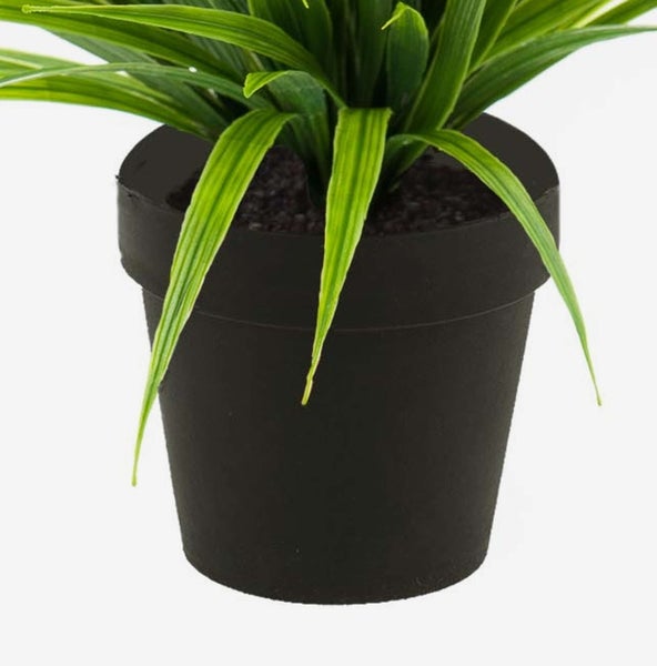 Künstliche Pflanze mit langen grünen Blättern in einem schwarzen Kunststofftopf.