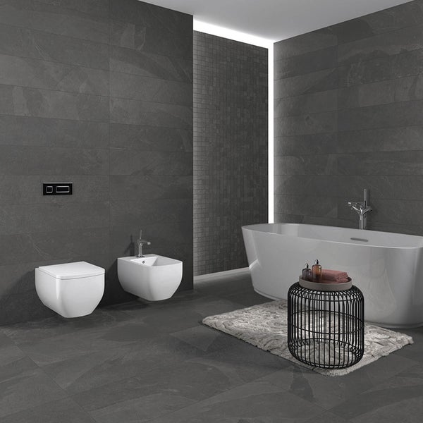 Modernes Badezimmer mit dunklen Fliesen, freistehender Badewanne, wandhängendem WC und Bidet.