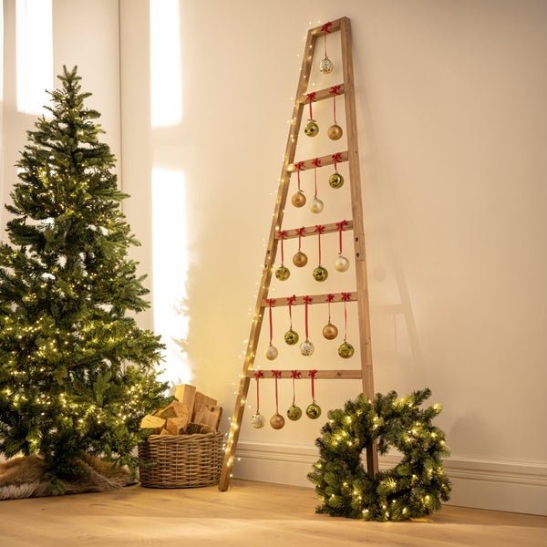 Weihnachtliche Raumdekoration mit einem künstlichen Weihnachtsbaum, einer Holzleiter als Weihnachtsbaumersatz mit Kugeln und einem Adventskranz.