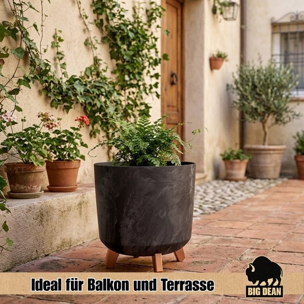Runder Pflanztopf mit Holzbeinen auf einer Terrasse stehend mit Farn bepflanzt, ideal für Balkon und Terrasse, Big Dean Logo.