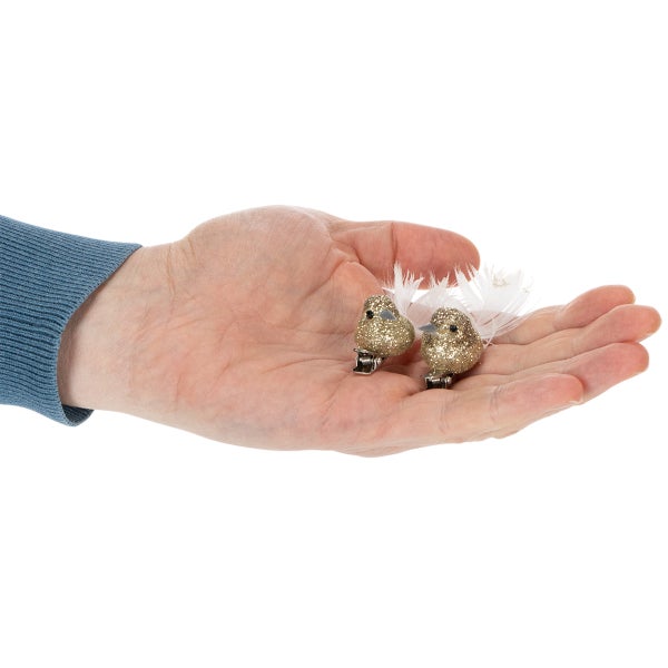 Zwei kleine Dekovögel mit Glitzer und Federn auf Clips in einer Hand zur Größenveranschaulichung.