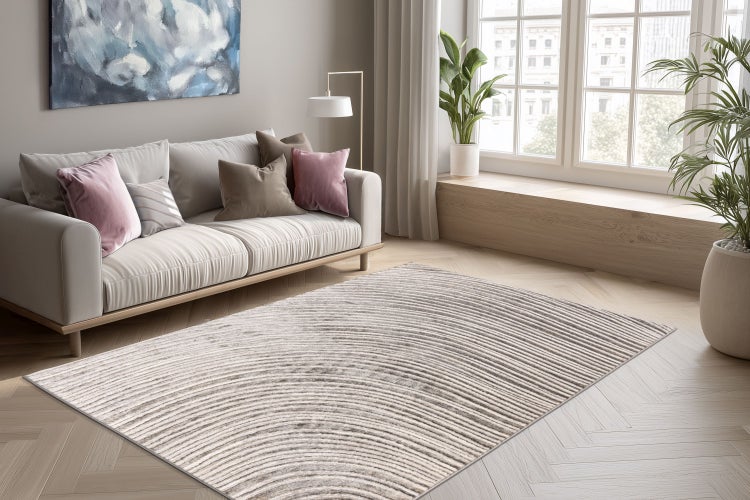 Wohnzimmer mit modernem Sofa und einem Teppich mit kreisförmigem Streifenmuster auf einem hellen Fischgrätparkett.