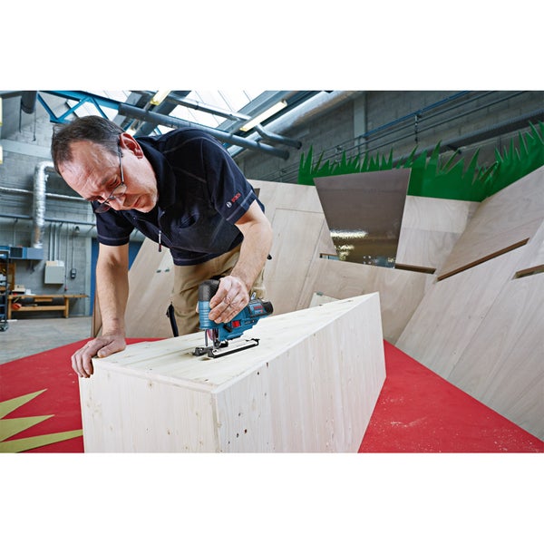 Ein Handwerker arbeitet mit einer Bosch Stichsäge an einer Holzkonstruktion in einer hellen, organisierten Werkstatt.
