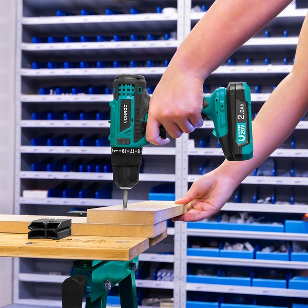 Vonroc Akku-Bohrschrauber 20 Volt bohrt in ein Holzbrett auf einer Werkbank in einer hellen, organisierten Werkstatt.