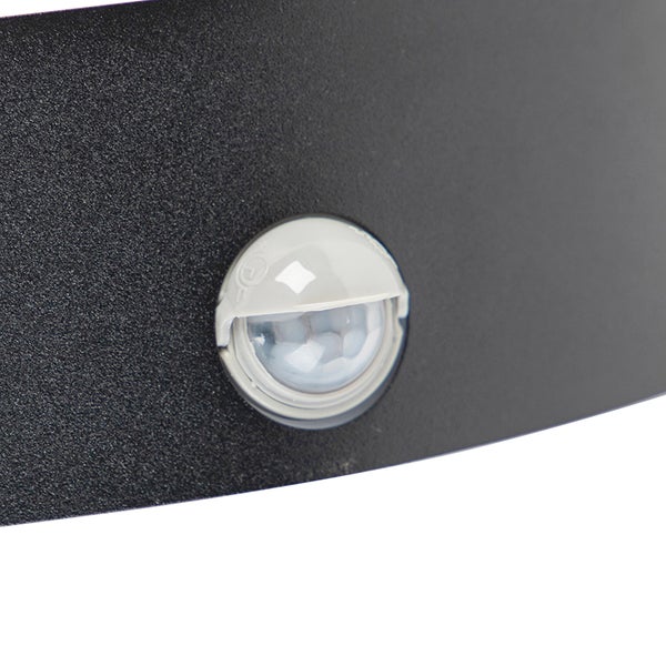 Nahaufnahme eines runden Bewegungsmelders integriert in ein schwarzes Gehäuse einer Außenleuchte.