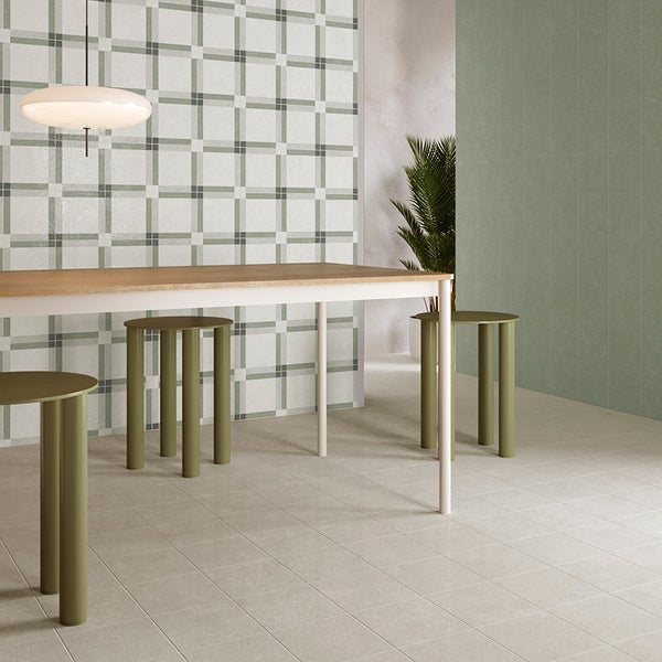 Moderne Wand- und Bodenfliesen in einem Essbereich mit kariertem Wandmuster und schlichten Fliesen, ergänzt durch einen Holztisch und Designhocker.