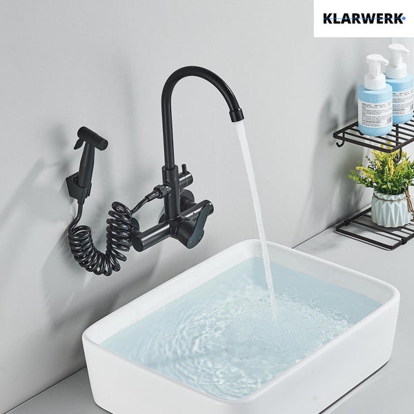 Wandmontierte schwarze Badarmatur mit hohem Auslauf und Bidetbrause am Spiralschlauch über weißem Waschbecken. Klarwerk Logo.