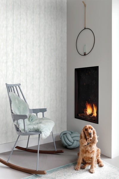 Wohnzimmer mit Kamin, Schaukelstuhl, dekorativem Knoten und Hund