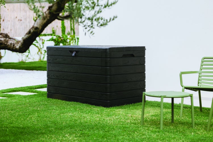 Garten Szene mit einer schwarzen Aufbewahrungsbox und grünen Gartenmöbeln auf Rasen.
