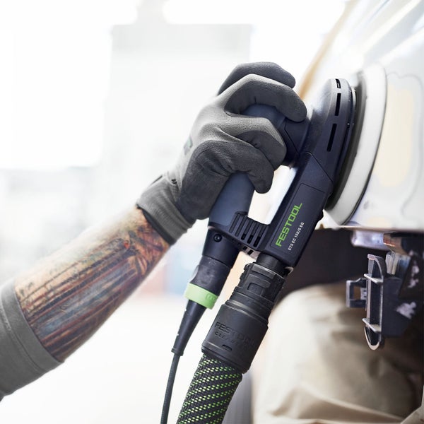Eine Person mit Schutzhandschuhen benutzt einen Exzenterschleifer der Marke Festool, Modell ETS EC 150/5 EQ, an einem Werkstück.
