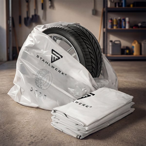 Ein Reifen in einem weißen Reifensack mit Stahlwerk Logo und Positionsmarkierungen in einer hellen Werkstatt, daneben ein Stapel Kunststoffhüllen.