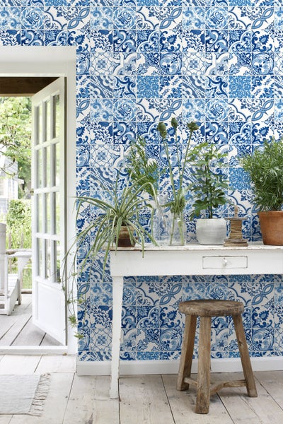 Dekoratives Interieur mit blau gemusterter Wand, Tisch und Pflanzen