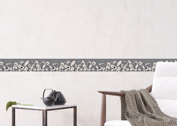 Tapetenbordüre mit floralem Muster an einer Wand in einem modern eingerichteten Wohnzimmer mit Sessel und Beistelltisch.