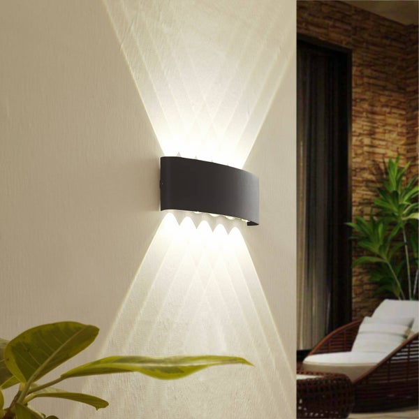 Moderne schwarze gewölbte Außenwandleuchte an einer Wand mit Lichtstrahlen nach oben und unten in einem Außenbereich.