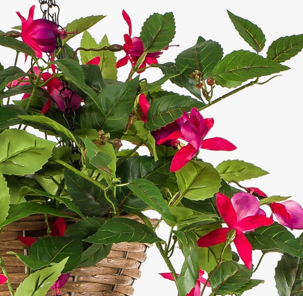Künstliche Fuchsia in einer Hängeampel aus Korbgeflecht mit pink-violetten Blüten und grünen Blättern.
