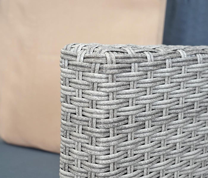 Nahaufnahme einer grauen Polyrattan-Geflechtstruktur eines Gartenmöbels.