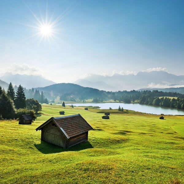 Landschaft mit Wiesen, See und kleinen Hütten