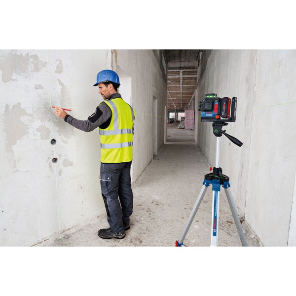 Ein Arbeiter markiert mit einem Stift eine Linie, die von einem Kreuzlinienlaser an die Wand projiziert wird.