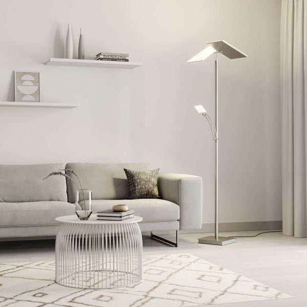 Moderne LED-Stehleuchte mit quadratischem Deckenfluter und verstellbarem Lesearm in einem hellen Wohnzimmer mit grauem Sofa und weißem Tisch.