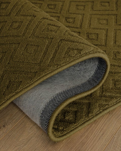 Strukturierter Teppich mit geometrischem Muster, dunkelgrün, auf hellem Bodenbelag in Holzoptik.