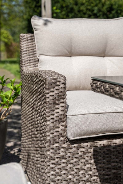 Detailansicht eines Gartenstuhls aus Polyrattan mit gepolsterten Sitz- und Rückenkissen.
