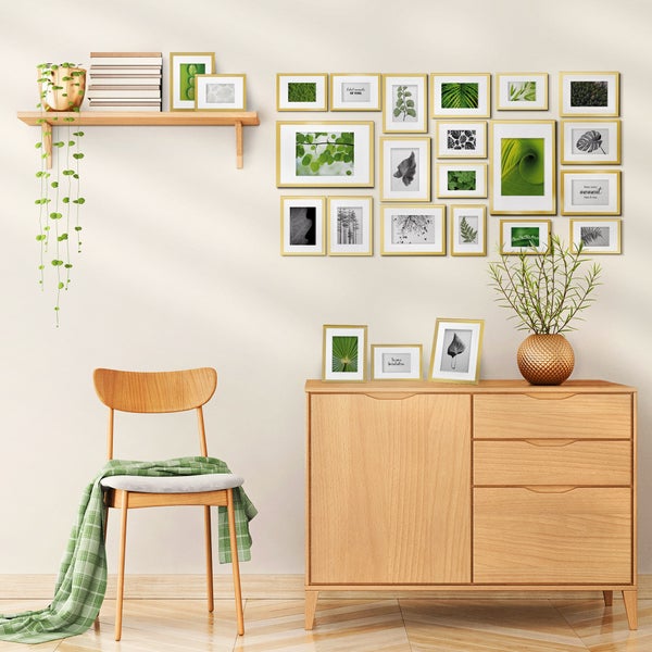 Eine Wand mit einer Bildergalerie aus zahlreichen gerahmten Pflanzenbildern über einer hölzernen Anrichte mit Stuhl und hängender Pflanze.