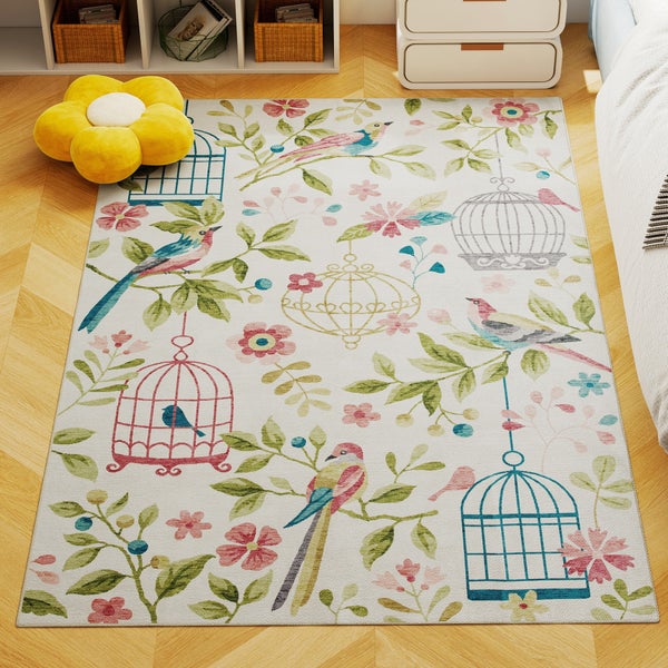 Bunter Kinderteppich mit Vögeln, Käfigen und Blumen auf hellem Parkettboden in einem hellen Zimmer mit gelbem Sitzkissen.