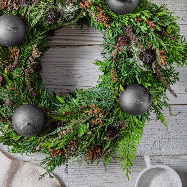 Dekorativer Adventskranz mit Kerzen, Tannenzweigen und Ornamenten als festliche Dekoration