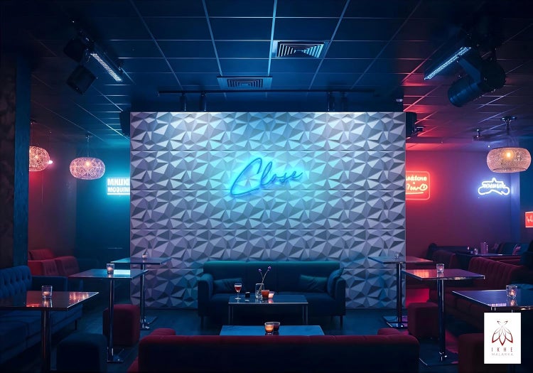 Moderne Lounge mit dreidimensionaler Wandverkleidung, Neon Schriftzug und Sitzgelegenheiten in stimmungsvoller Beleuchtung.