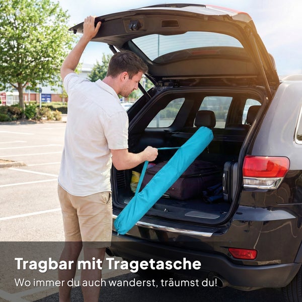 Ein Mann verstaut eine blaue Tragetasche im organisierten Kofferraum eines Autos auf einem hellen Parkplatz zur Demonstration der Portabilität.