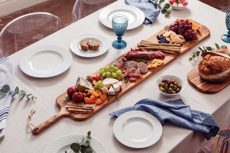 Gedeckter Tisch mit Wurst, Käse, Obst, Brot und Geschirr