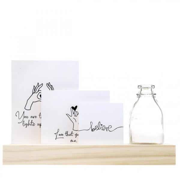 Dekorative Zettel mit Schriftzug und eine Glasflasche auf einem Regal