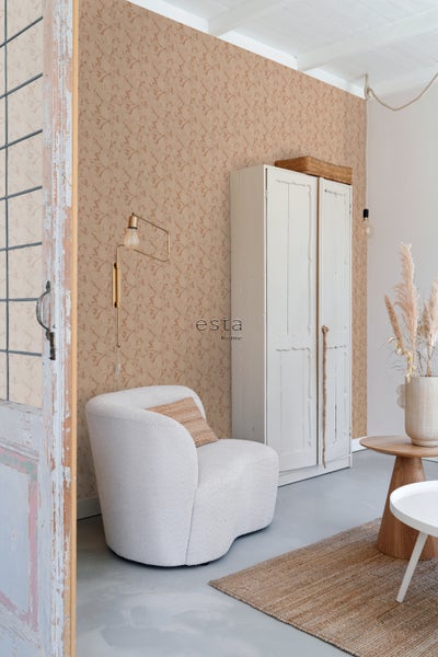 Wohnzimmer mit floral gemusterter Tapete, Sessel, Schrank und Teppich