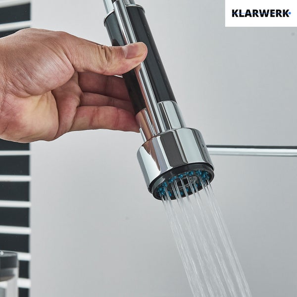 Hand hält die ausziehbare Brause einer Küchenarmatur mit fließendem Wasser. Klarwerk Logo.