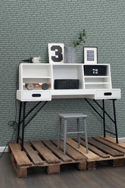 Weißer Schreibtisch mit Ablagefächern, schwarzem Metallgestell und grauem Hocker auf Holzpalette