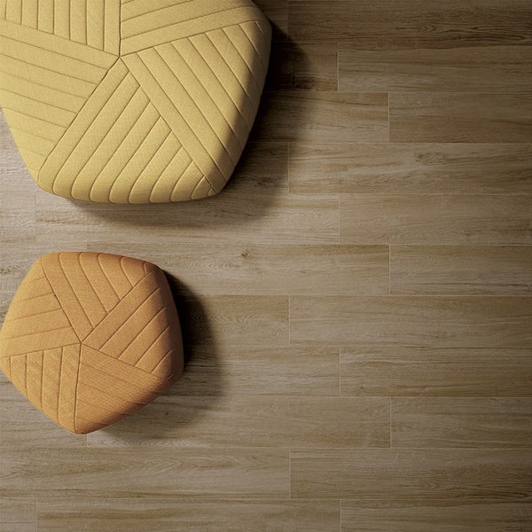 Draufsicht auf einen Bodenbelag aus Holzoptik Fliesen mit zwei gepolsterten Hockern in geometrischer Form und texturierter Oberfläche.