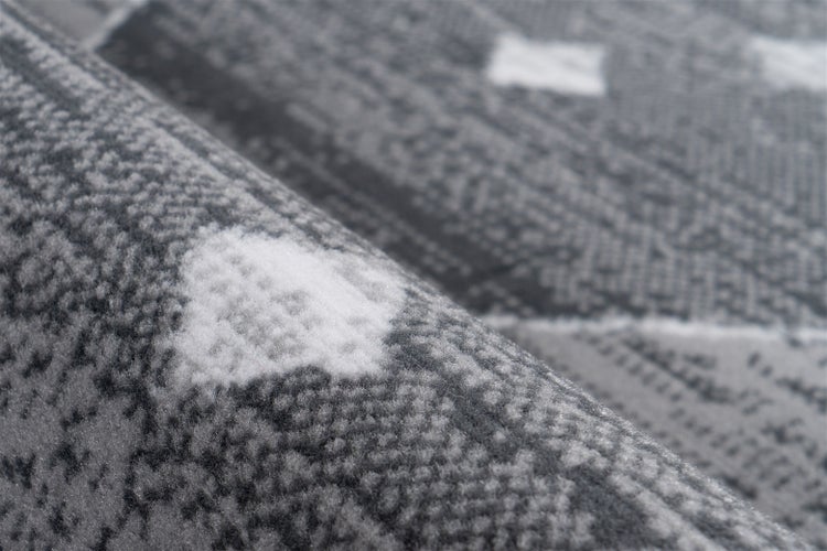 Detailansicht eines Teppichs mit abstrakten geometrischen Mustern und kurzfloriger Textur.