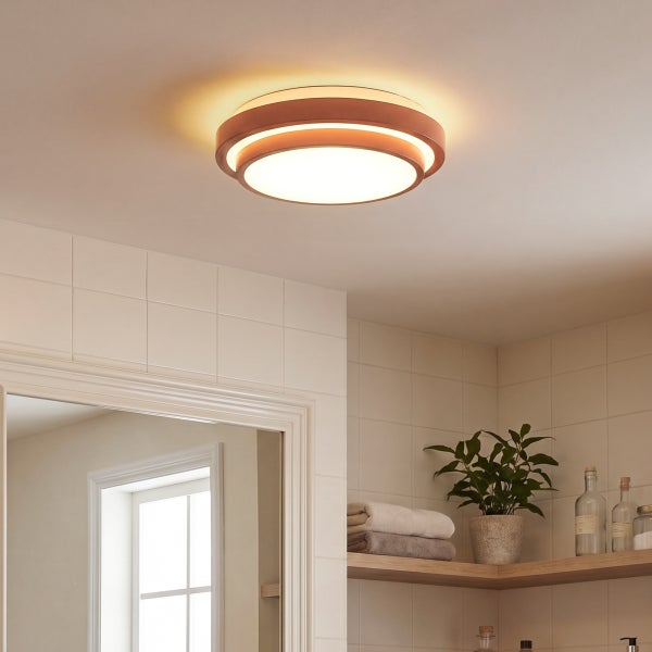 Moderne LED Deckenleuchte mit rundem Design installiert in einem Badezimmer mit Fliesen, Regal und Pflanze.
