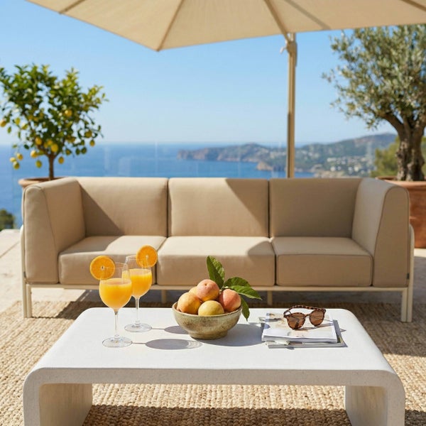 Helle Terrasse mit beigem Outdoor-Sofa, weißem Couchtisch, Sonnenschirm, Meerblick und Zitronenbaum.