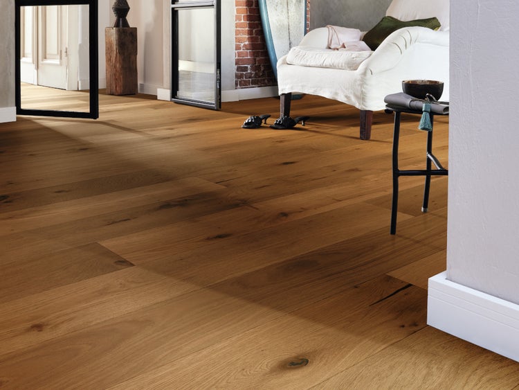 Wohnraum mit verlegtem Parkettboden aus Eichenholz, rustikale Optik mit sichtbaren Astlöchern und natürlicher Maserung, gemütliches Ambiente.