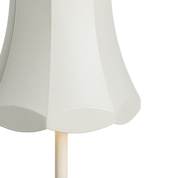 Nahaufnahme eines weißen, glockenförmigen Lampenschirms mit gewelltem Rand auf einem Lampenfuß.