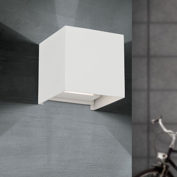 Weiße würfelförmige Wandleuchte mit Up-und-Down-Lichteffekt an einer strukturierten Wand.