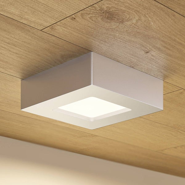 Quadratische LED-Deckenleuchte zur Aufbaumontage an einer Holzdecke mit Gehäuse aus Metall und leuchtendem Paneel.
