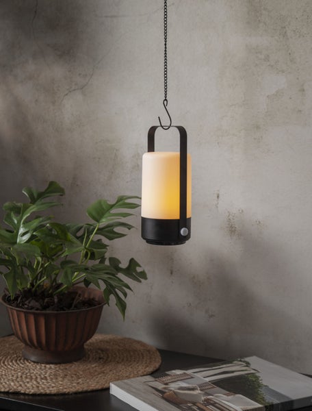 Hängelampe mit Kettenaufhängung neben einer Zimmerpflanze auf einem Tisch